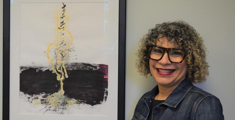 Dr. 阿尔玛·霍夫曼, an assistant professor of graphic design, 与她的画作“Micah 4”合影，这幅画被《十大玩彩信誉平台》评为2021年100件最佳艺术品之一. 
